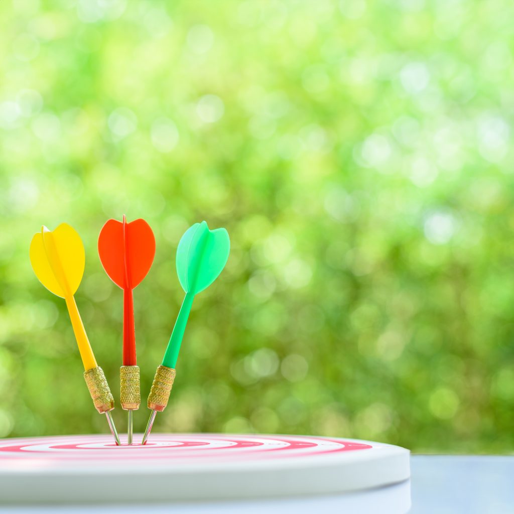 Side view of 3 color darts hitting the center area of a bullseye